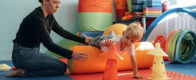 Enfant avec enseignant pendant exercices de motricité dans une salle de jeu